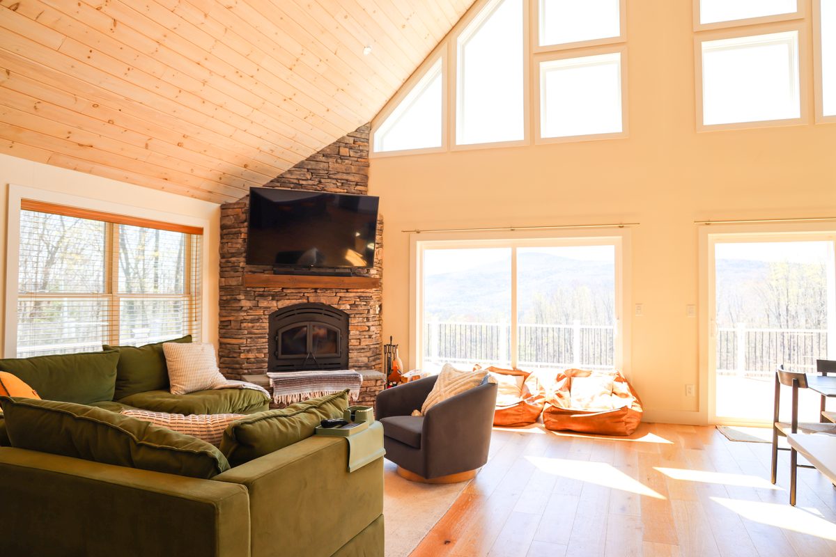 The living room fireplace framed by mountain-facing windows